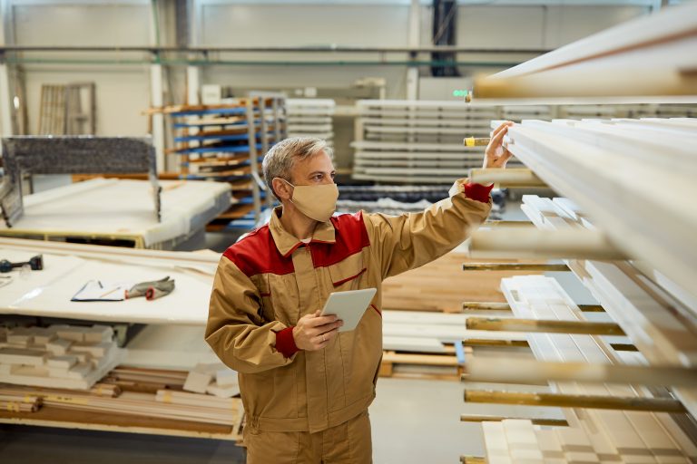 male worker using touchpad while checking stock at carpentry wor